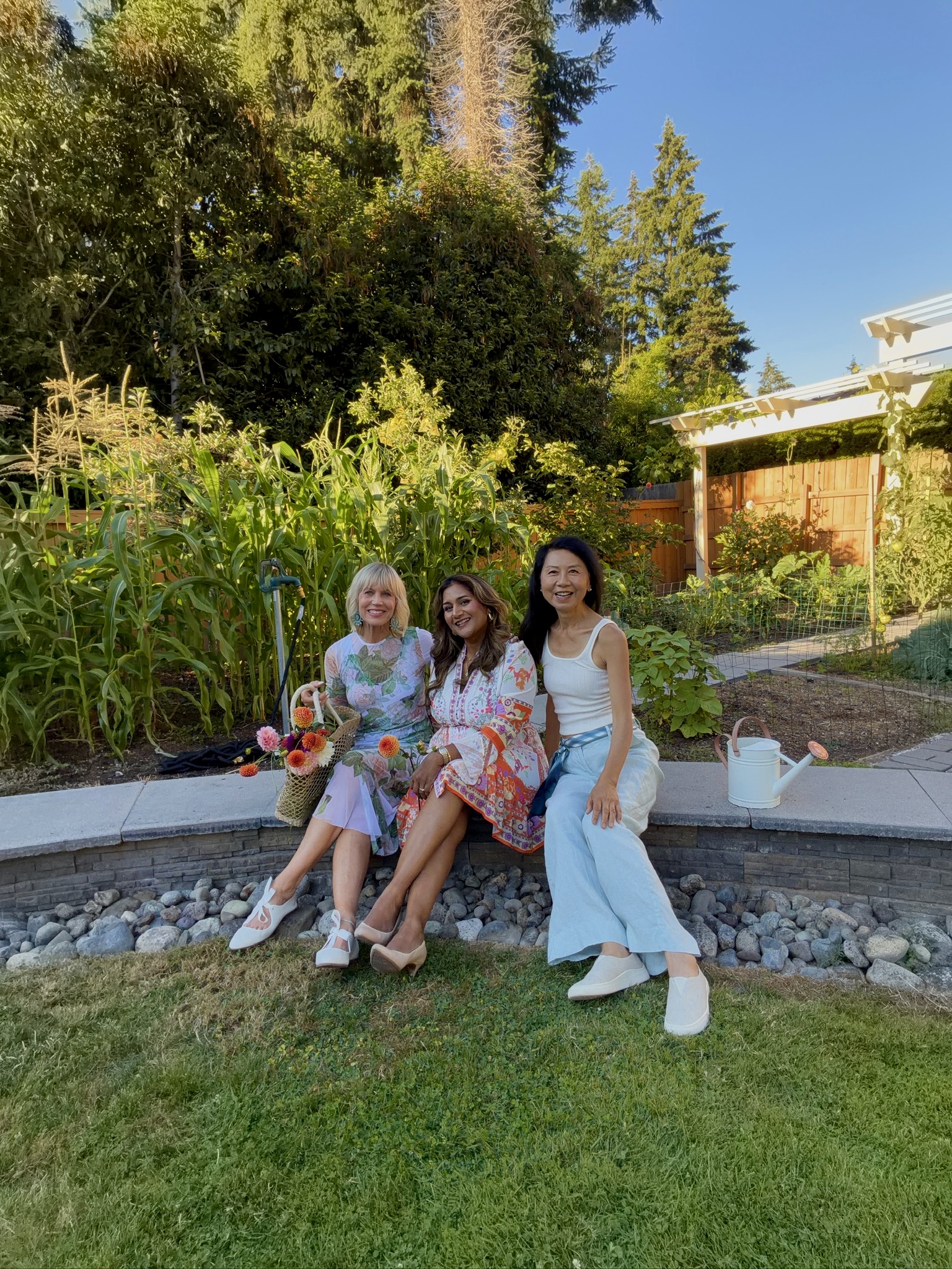 Janney with two friends sitting on the garden wall in front of the corn