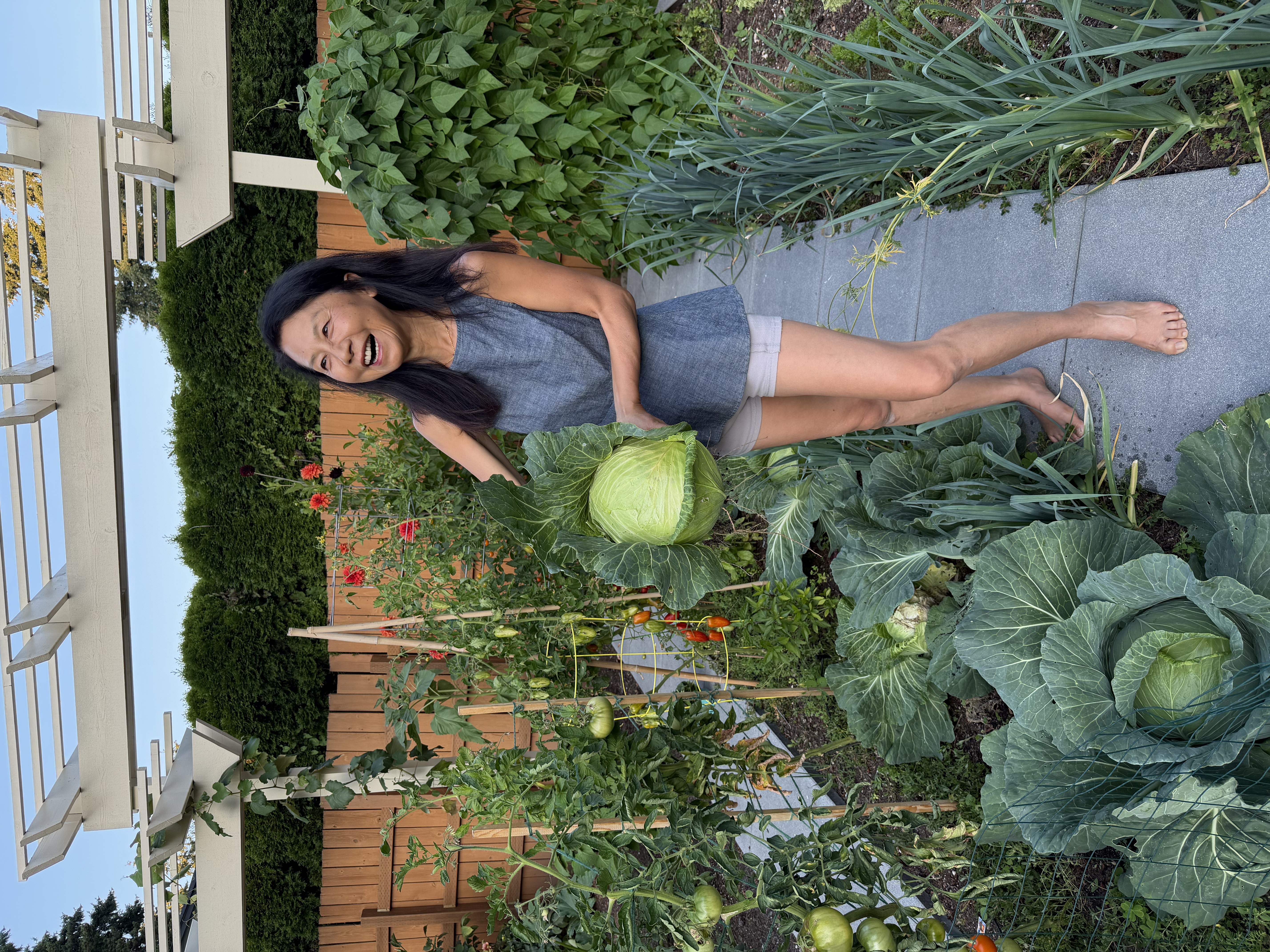 Janney holding a cabbage in her backyard garden