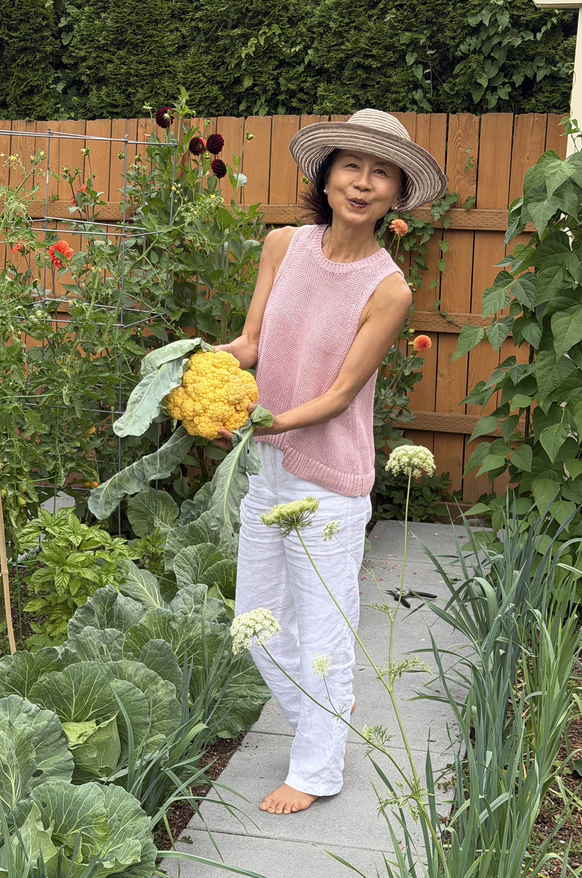 Janney in a sun hat holding a yellow cauliflower