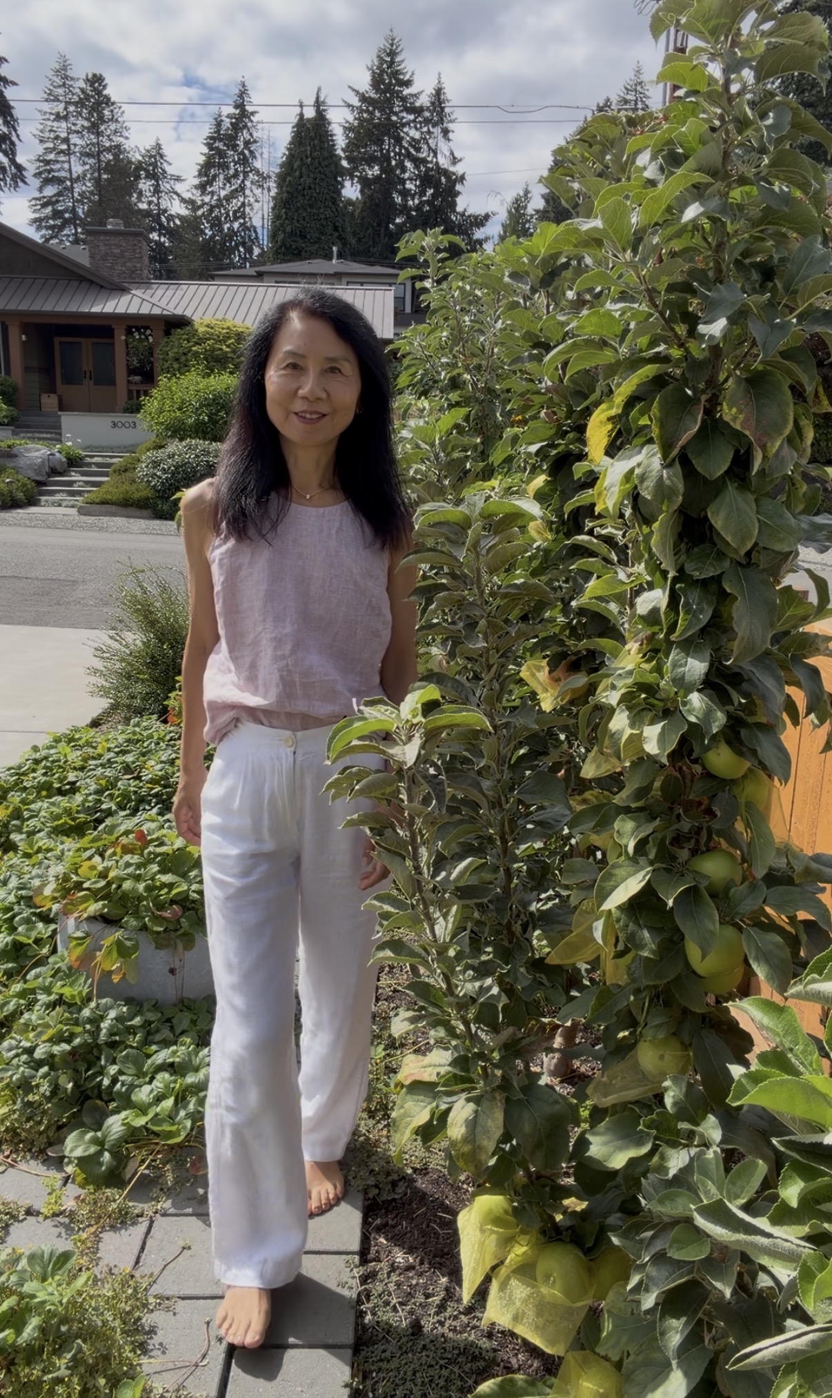 Janney standing beside a columnar apple tree roughly her own height
