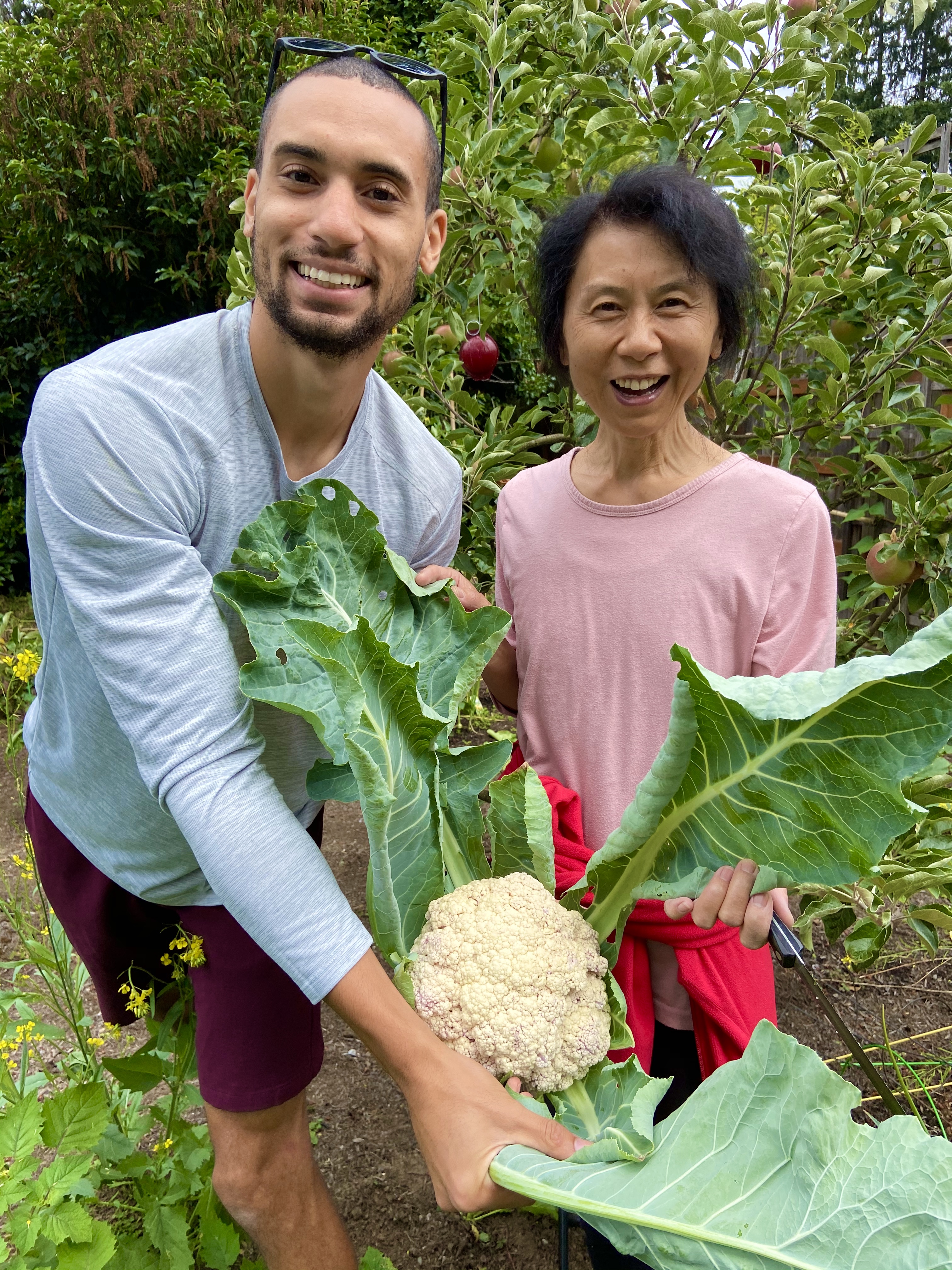 Janney and her son holding up a cauliflower with its leaves